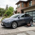 Tesla Model Y parked at a modern American home with a residential EV charging station.