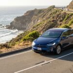 Tesla Model X driving along a scenic California coastal highway.